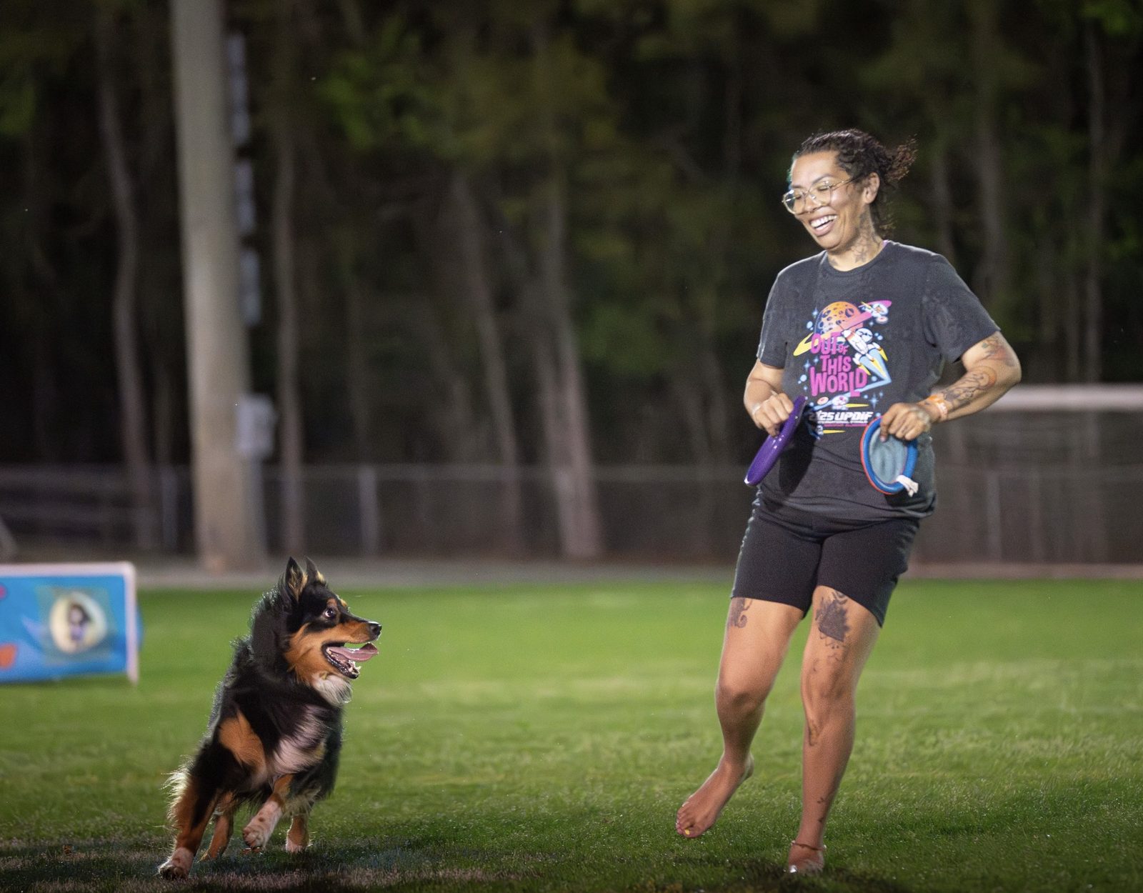 Jasmine running across a field with a dog at a disc dog event
