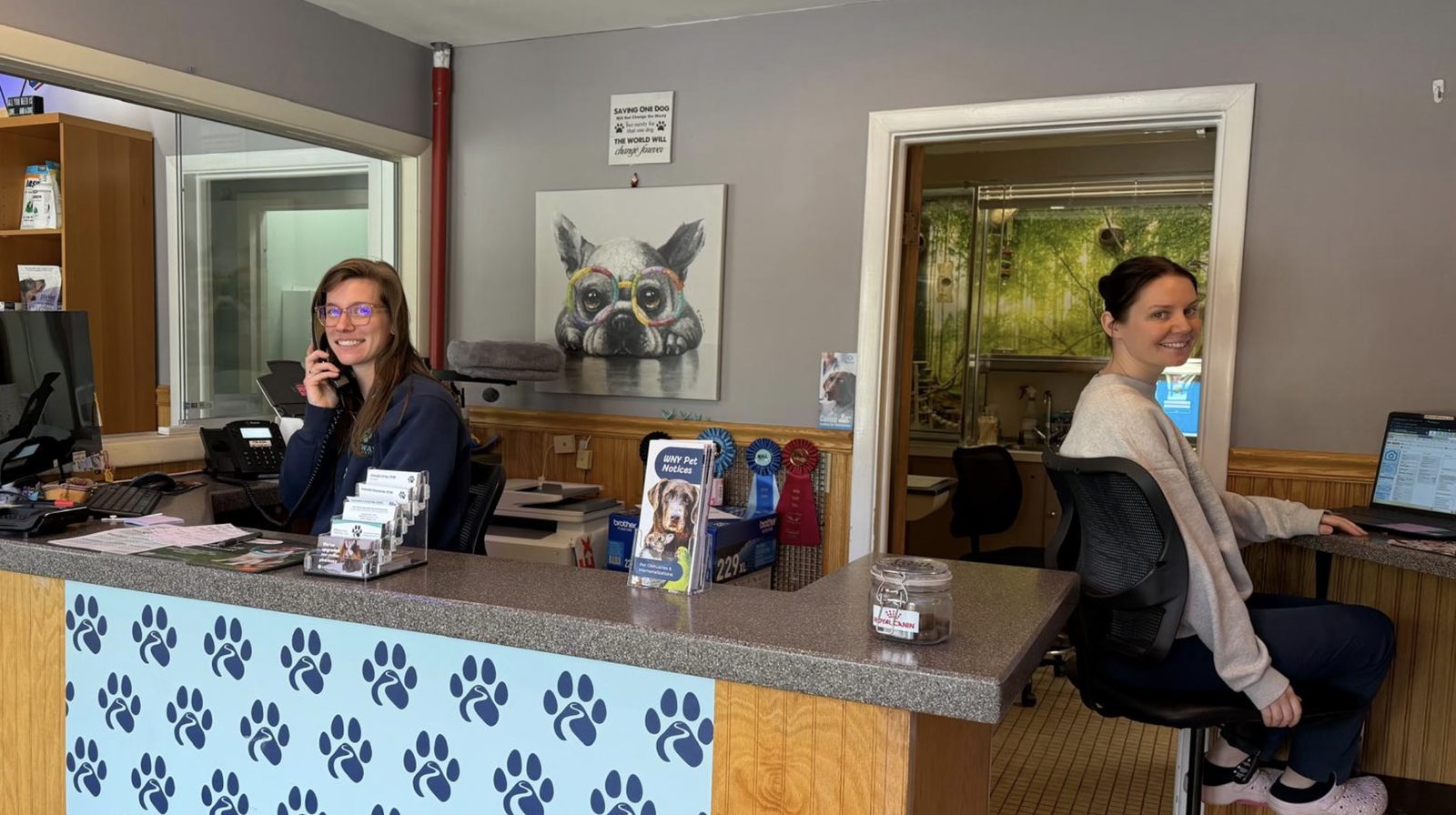 Two Pathways team members at the front desk, one on the phone and one working at the reception computer